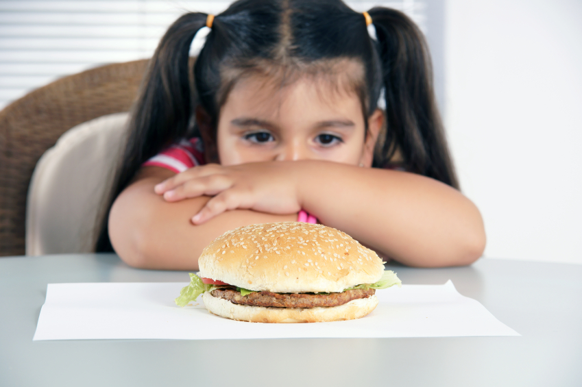 girl staring longingly at a hamburger